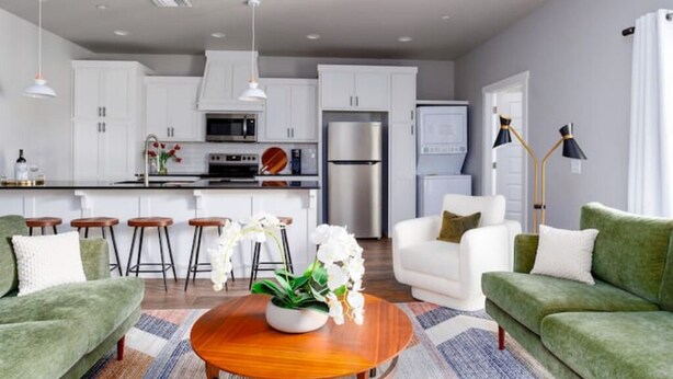 A modern kitchen with white cabinets, a stainless steel refrigerator, and a central island with stools. - H3/H5 Spacious & Urban Modern Condo - 2 units! (Oklahoma City)