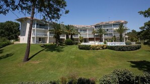 Et hotel med flere etager, altaner, en velholdt græsplæne og palmer.