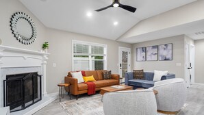 A living room with a fireplace, a ceiling fan, and a large mirror on the wall.