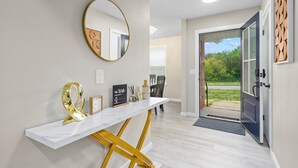 A modern entryway with a marble console table, a gold mirror, and a welcome sign.