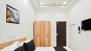 A hotel room with a bed, a wardrobe, a painting, a TV, and a telephone. - Classic Kokapet Near GAR (Hyderabad)