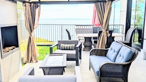 An outdoor patio with wicker furniture, a table, and a grill. - New Oceanfront Luxury Suite with a breathtaking  view of downtown Vancouver, (Bowen Island)