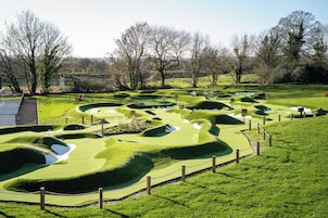 Un campo de golf con terreno ondulado y trampas de arena.