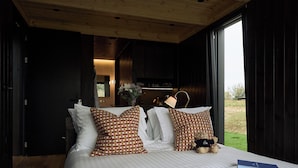 Un dormitorio con una cama grande, dos almohadas estampadas, un oso de peluche y un libro sobre la cama.