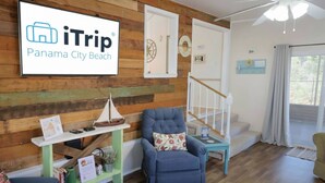 Egy szoba, melyben van egy fa fal, egy kék karosszék, egy kis asztal, rajta egy hajómodell, egy lépcsőház, és egy tábla, melyen az szerepel: „iTrip Panama City Beach”.
