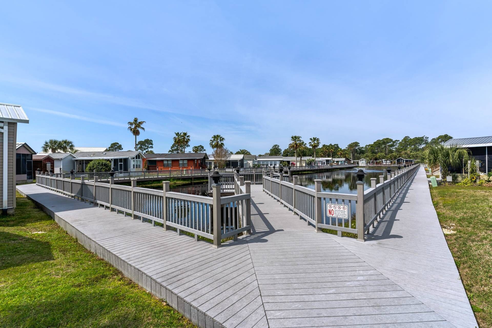 A waterfront boardwalk with wooden railings, a canal, and buildings in the background.