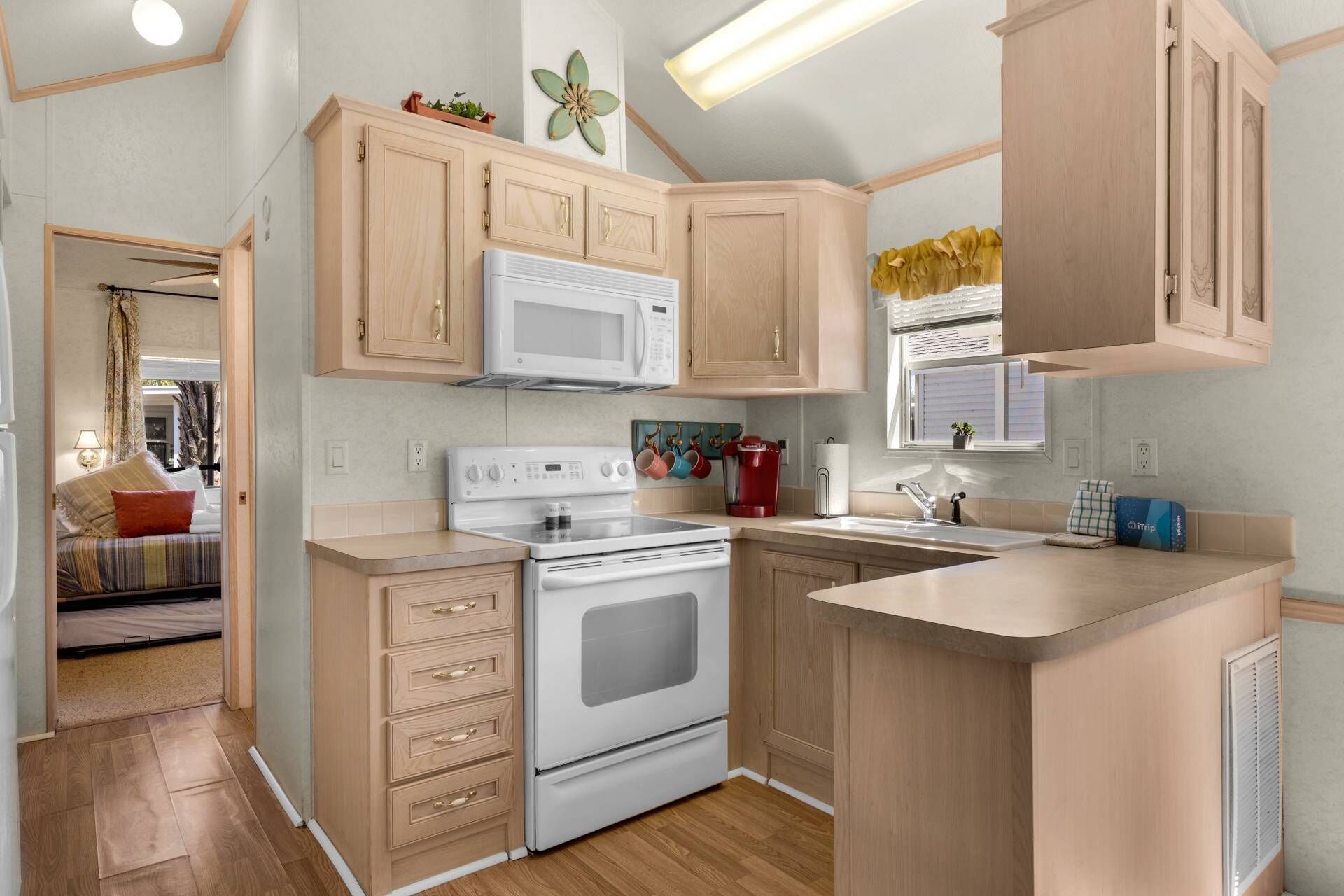 A compact kitchen with wooden cabinets, a microwave, a stove, and a sink.