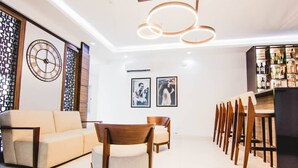 A modern living room with a sofa, chairs, a dining table, and a bar area with bottles. - MISAN HOTEL (Lekki)