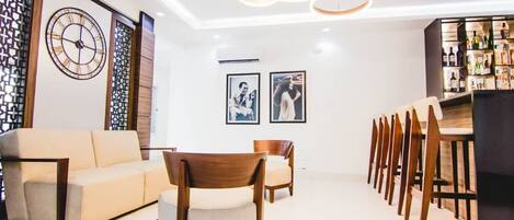 A modern living room with a sofa, chairs, a dining table, and a bar area with bottles.