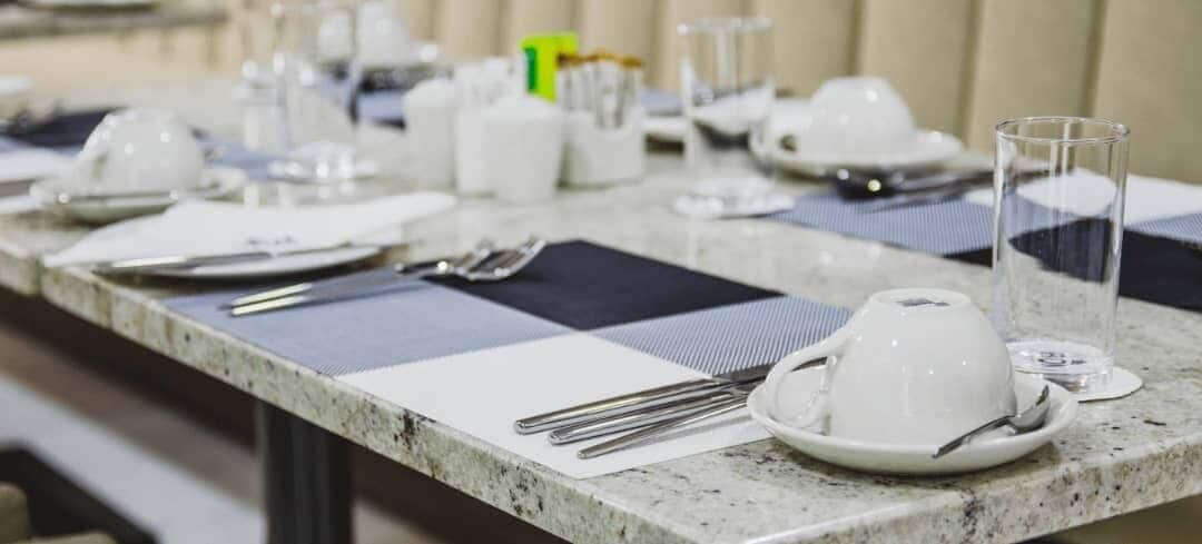 A table set with white plates, cutlery, and a glass.