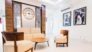 A modern lobby with a sofa, two armchairs, a coffee table, a decorative wall clock, and framed photographs. - MISAN HOTEL (Lekki)