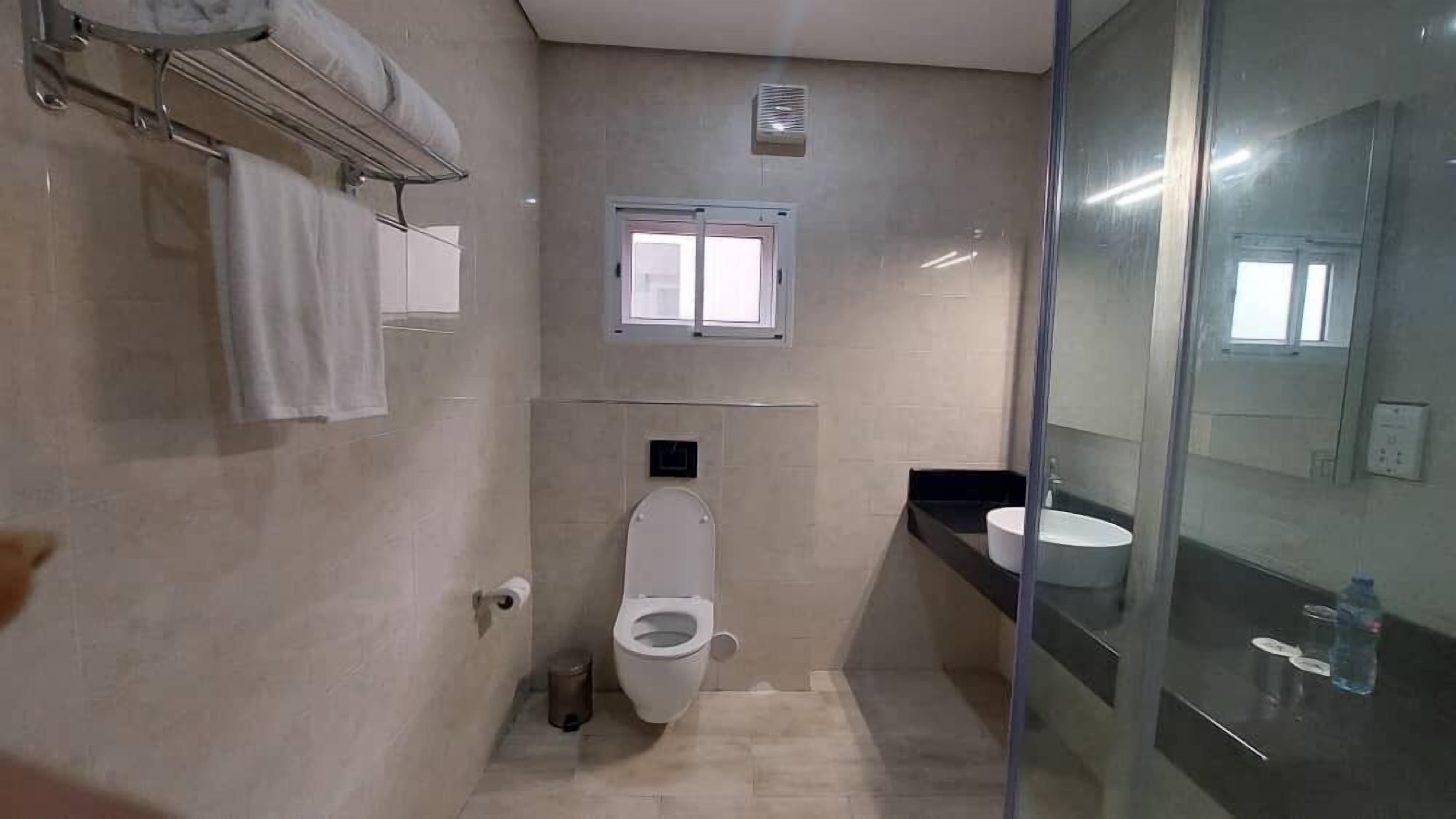 Une salle de bain comprenant des toilettes, un lavabo, une fenêtre et un porte-serviettes.