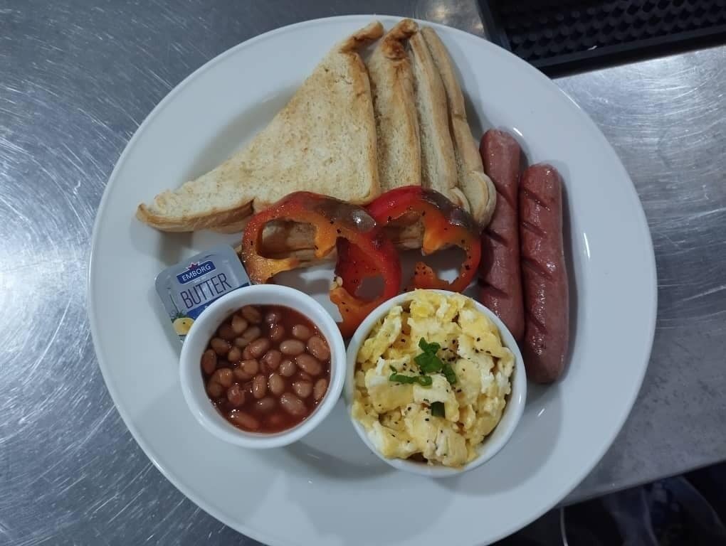A plate with toast, sausages, beans, scrambled eggs, and butter.