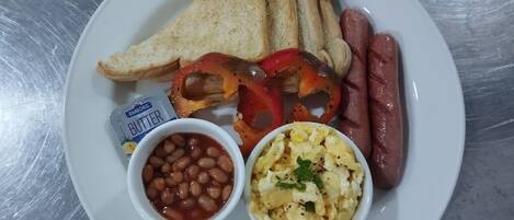 A plate with toast, sausages, beans, scrambled eggs, and butter.