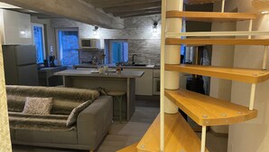 A modern kitchen with a central island, a dining area with a sofa, and a wooden spiral staircase. - Le logis des Glycines (6 adults 2 children) in the heart of the village of Nançay en Sologne (Nançay)
