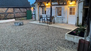 A traditional half-timbered house with a gravel patio, a table and chairs, and a small garden area. - Le logis des Glycines (6 adults 2 children) in the heart of the village of Nançay en Sologne (Nançay)