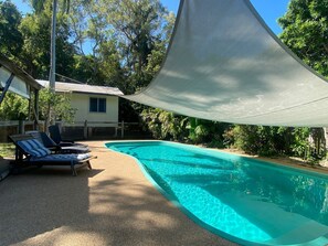 A swimming pool with lounge chairs, a shaded area, and a house in the background. - The Barracks Arcadia 1 (Arcadia)