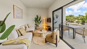 Un salon moderne comprenant un canapé, un fauteuil, une table basse ronde et un coin repas avec une table et des chaises.