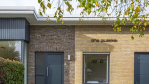 A modern building with a brick facade, a large window, and a door.