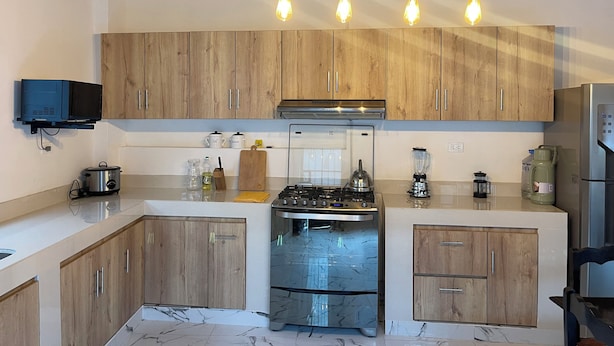 Una cocina moderna con armarios de madera, horno empotrado, estufa y microondas.