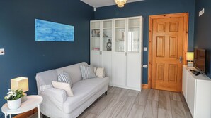 A modern living room with a grey sofa, a white cabinet, and a wooden door. - To The Beach! (Skerries)