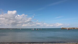 A coastal view with calm waters, sailboats, and a distant pier. - To The Beach! (Skerries)