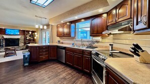 A modern kitchen with wooden cabinets, a built-in oven, and a large window. - All the Vibes Poolside in Trenton! (Trenton)