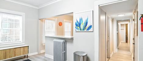 A modern interior with a radiator, a trash bin, and a hallway leading to another room.