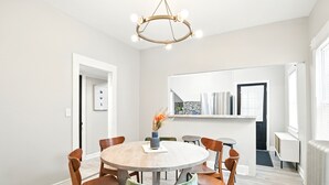 A modern dining area with a round table, wooden chairs, and a unique green cushioned bench. - Modern Victorian 3BR 2BA Apt with Parking (Springfield)