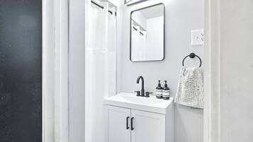 Een moderne badkamer met een witte wastafel, een spiegel en een handdoekhouder.