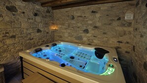 A stone-walled bathroom with a large, illuminated hot tub. - Pentasino Heritage Suites (Agios Theodoros)