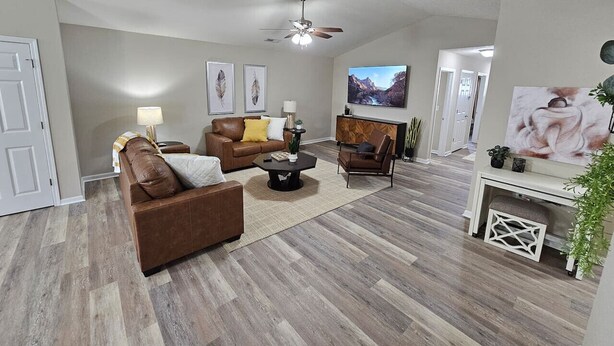 A living room with a brown leather sofa, a coffee table, a TV, and a fireplace. - Cozy Charming Cottage-Style Home (Hamilton)