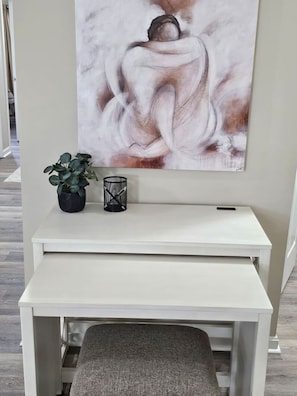 A white desk with a bench, a potted plant, and a candle holder.