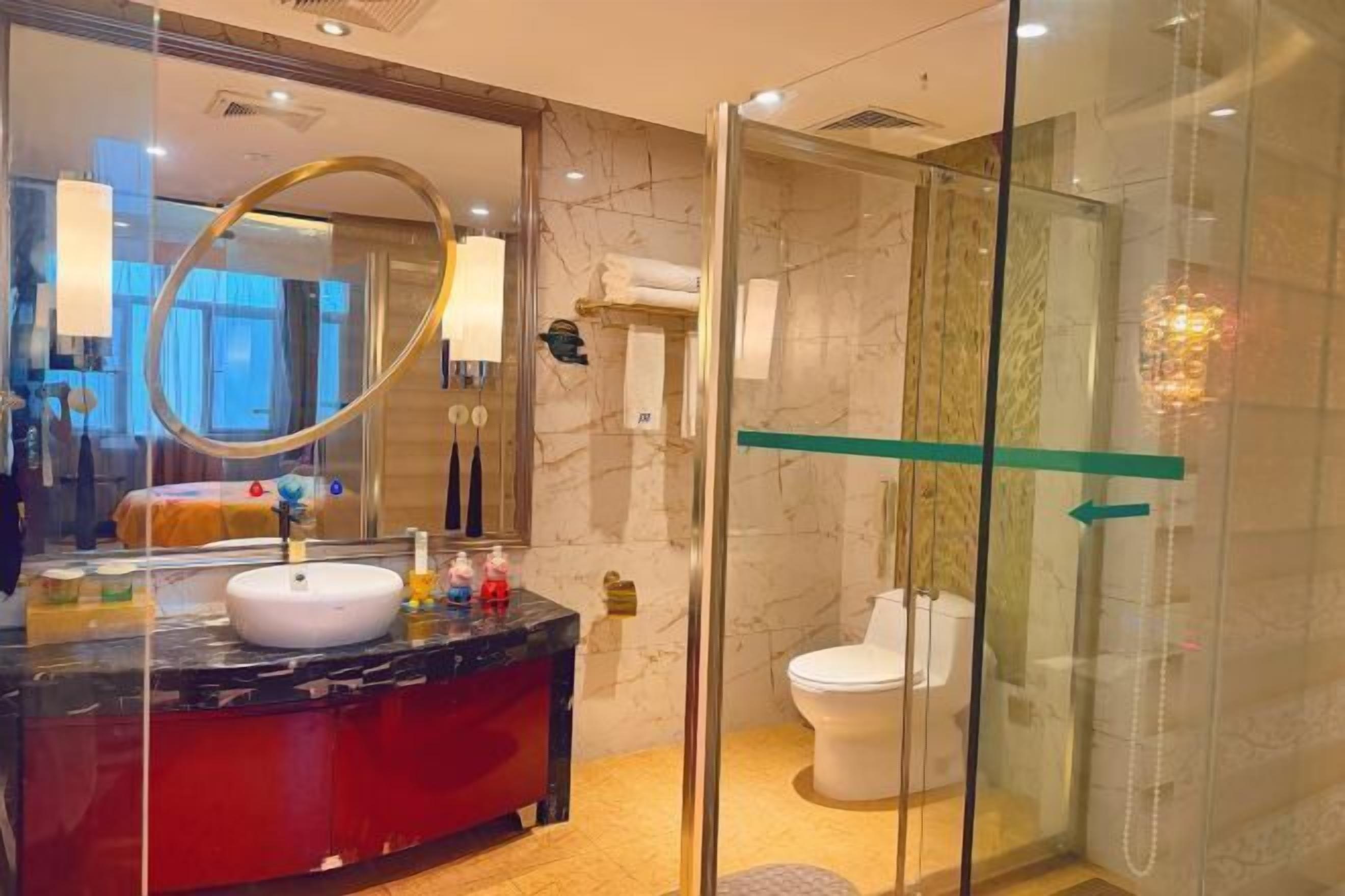 A modern bathroom with a glass-enclosed shower, a marble vanity, and a large mirror.