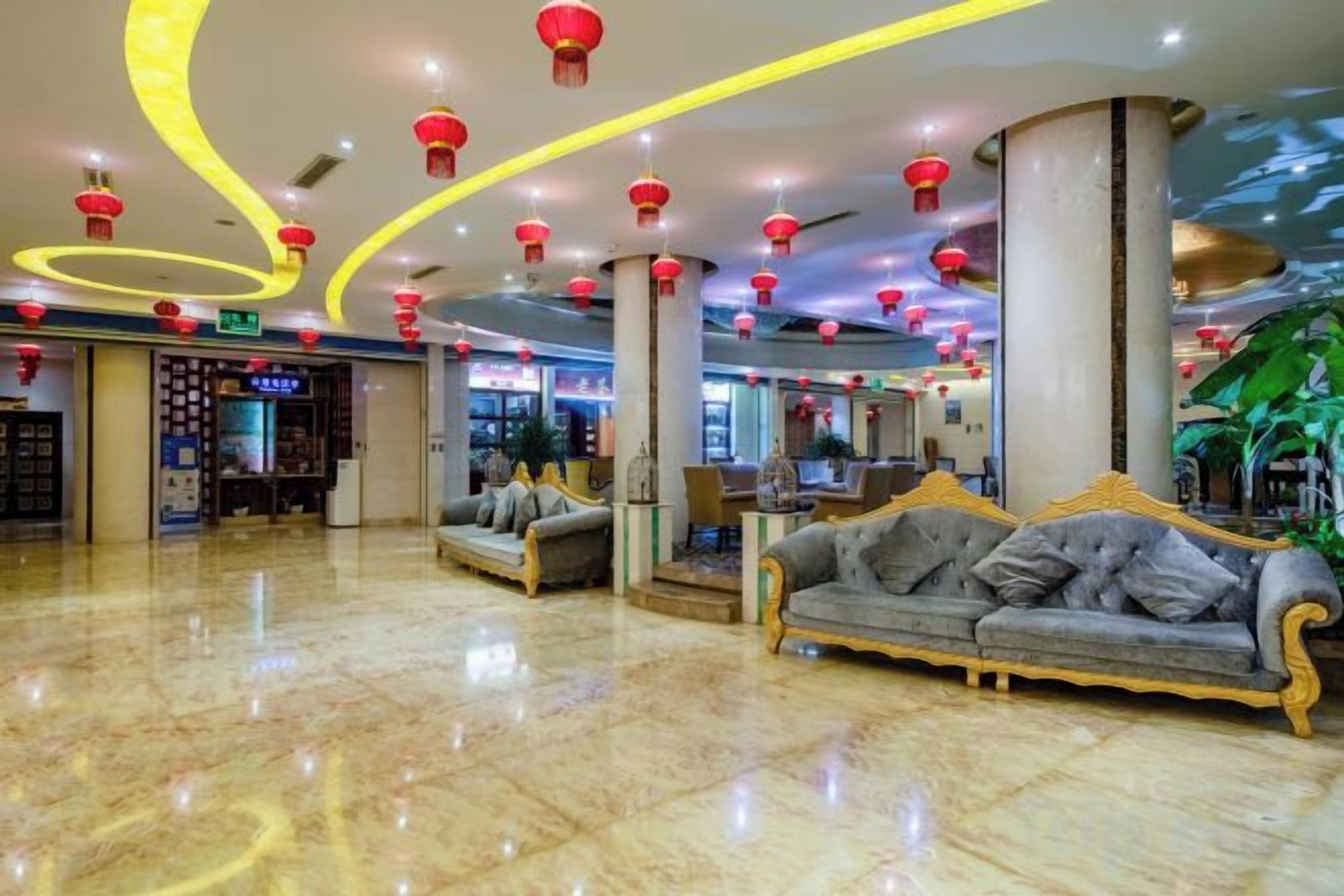 A hotel lobby with a marble floor, sofas, and red lanterns.