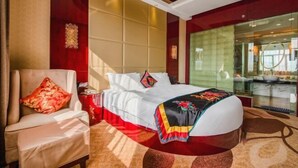 Habitación de hotel con cama, una silla, pared decorativa roja y una partición de vidrio.