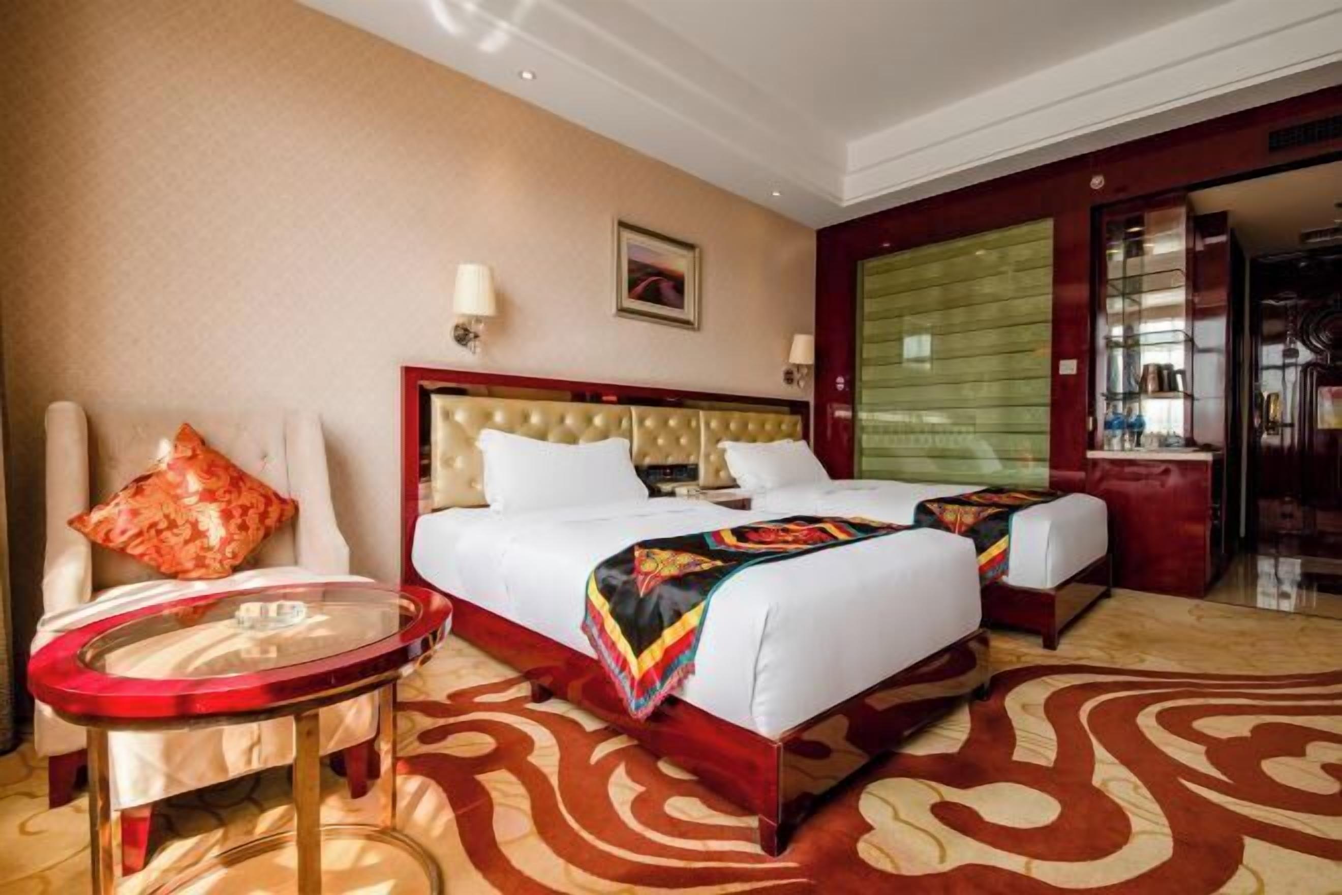 Ein Hotelzimmer mit einem großen Bett, einem kleinen runden Tisch, einem Sessel und Blick ins Freie.