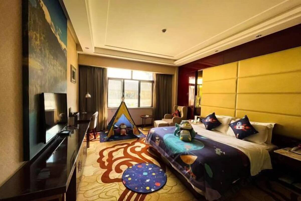 A hotel room with a bed, a TV, a desk, a chair, and a window.