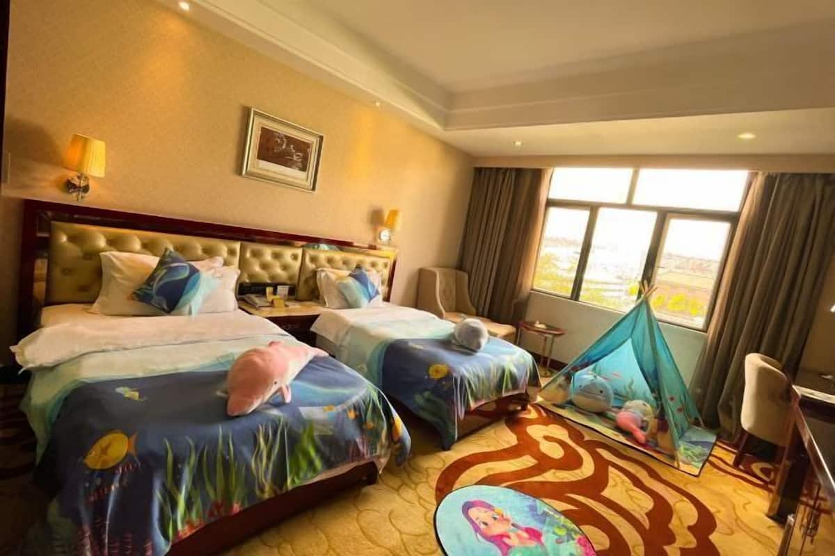 A hotel room with two beds, a large window, a view, and a tent-like structure.