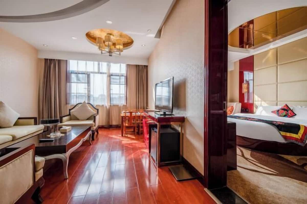 A hotel room with a sofa, a desk with a computer, a bed, and a TV.