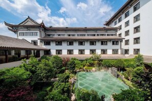 A traditional courtyard with a central green space, surrounded by buildings with white walls and tiled roofs. - Jianhua International Hotel (Chuxiong City)