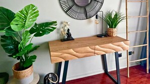 Une console en bois, ornée d’un miroir, d’une petite statue de Bouddha et d’une plante en pot.