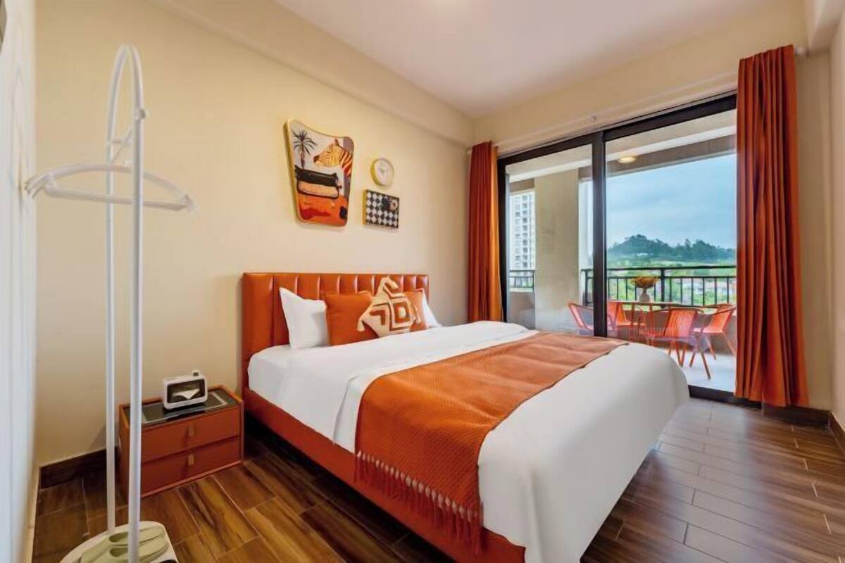 Une chambre d’hôtel avec un grand lit, une table de chevet, une horloge murale et une vue sur l’extérieur grâce à une porte-fenêtre coulissante.