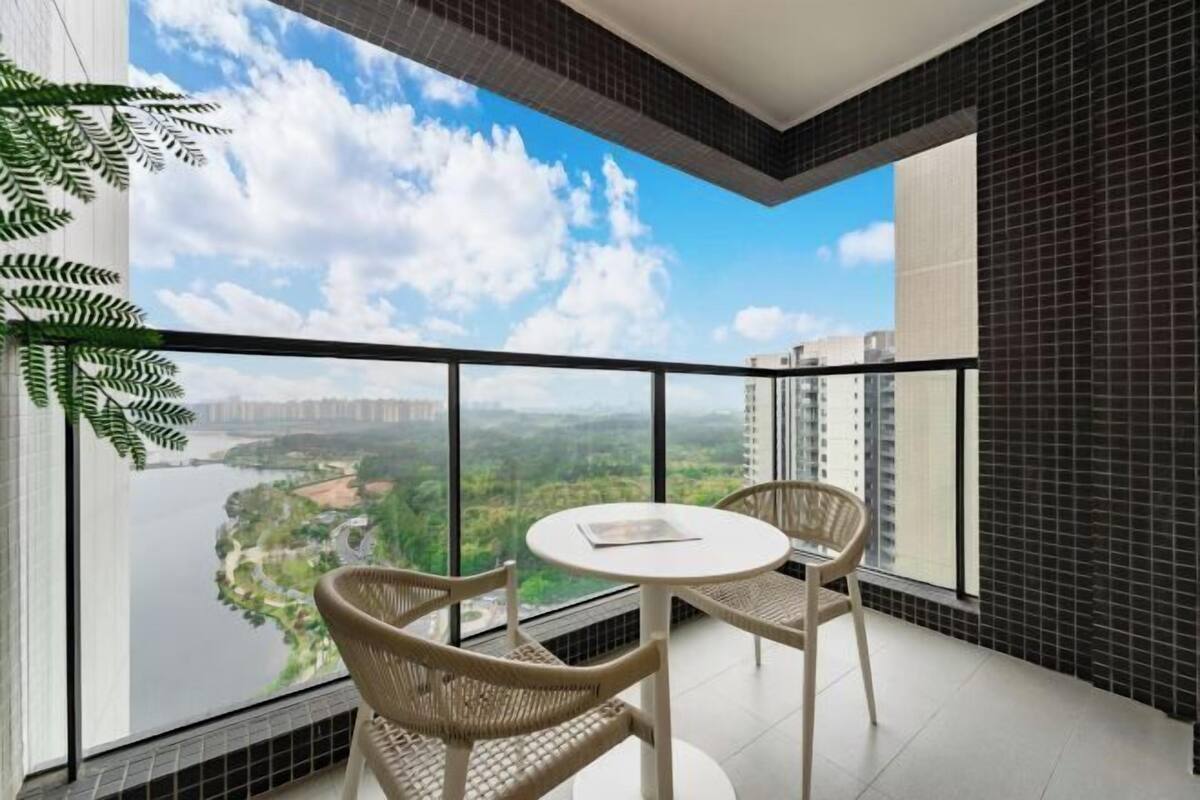 Un balcon donnant sur une rivière et sur la verdure, deux fauteuils en osier et une petite table ronde.