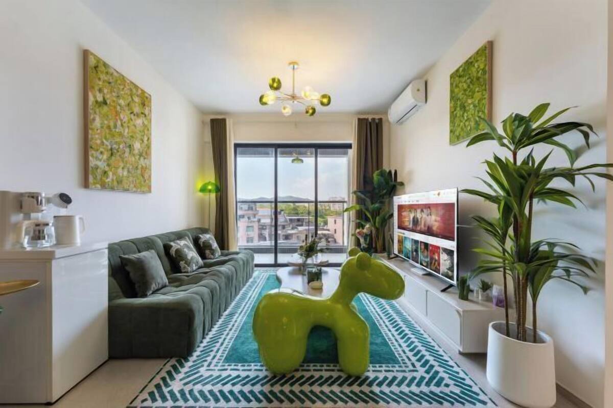 Un salon moderne avec un canapé, un élément de décoration vert, une table basse et un téléviseur.