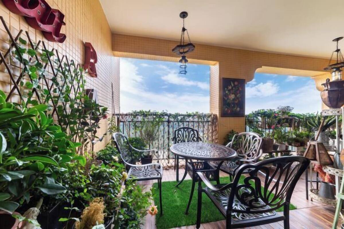 Une terrasse avec une table ronde et des chaises, entourée de plantes en pot et offrant une vue sur le ciel.