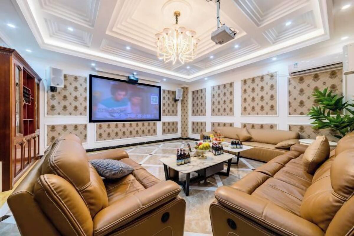 Un vaste salon doté de canapés en cuir, d’un grand téléviseur à écran plat et d’un lustre.