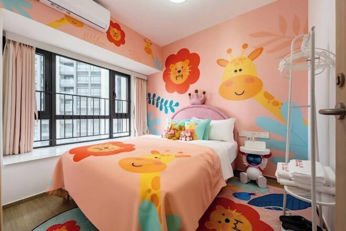 Une chambre d’enfant avec un lit, une fenêtre et un mur décoré de motifs représentant des animaux.