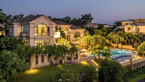 A large, luxurious house with a swimming pool, surrounded by lush greenery and palm trees. - Jushu Holiday Villa (Huadu Palm Island) (Guangzhou)