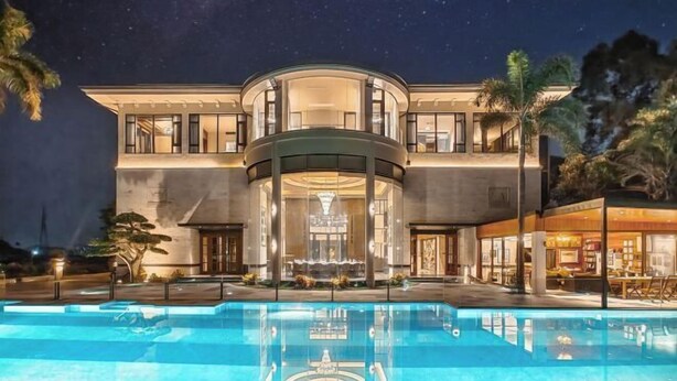 Un hôtel moderne doté d’une grande piscine, d’une structure circulaire en verre et d’une façade bien éclairée.
